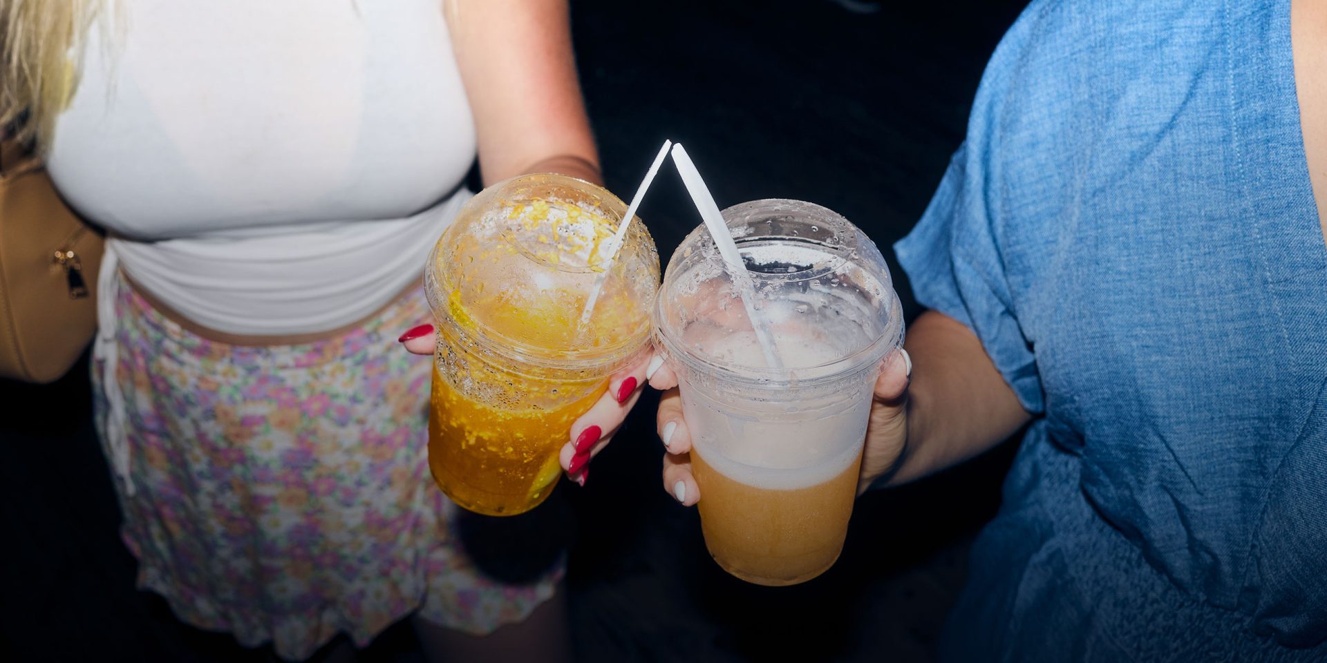 Zwei Frauen halten einen Getränkebecher mit Strohhalm. Symbolbild für "Debit- oder Kreditkarte"
