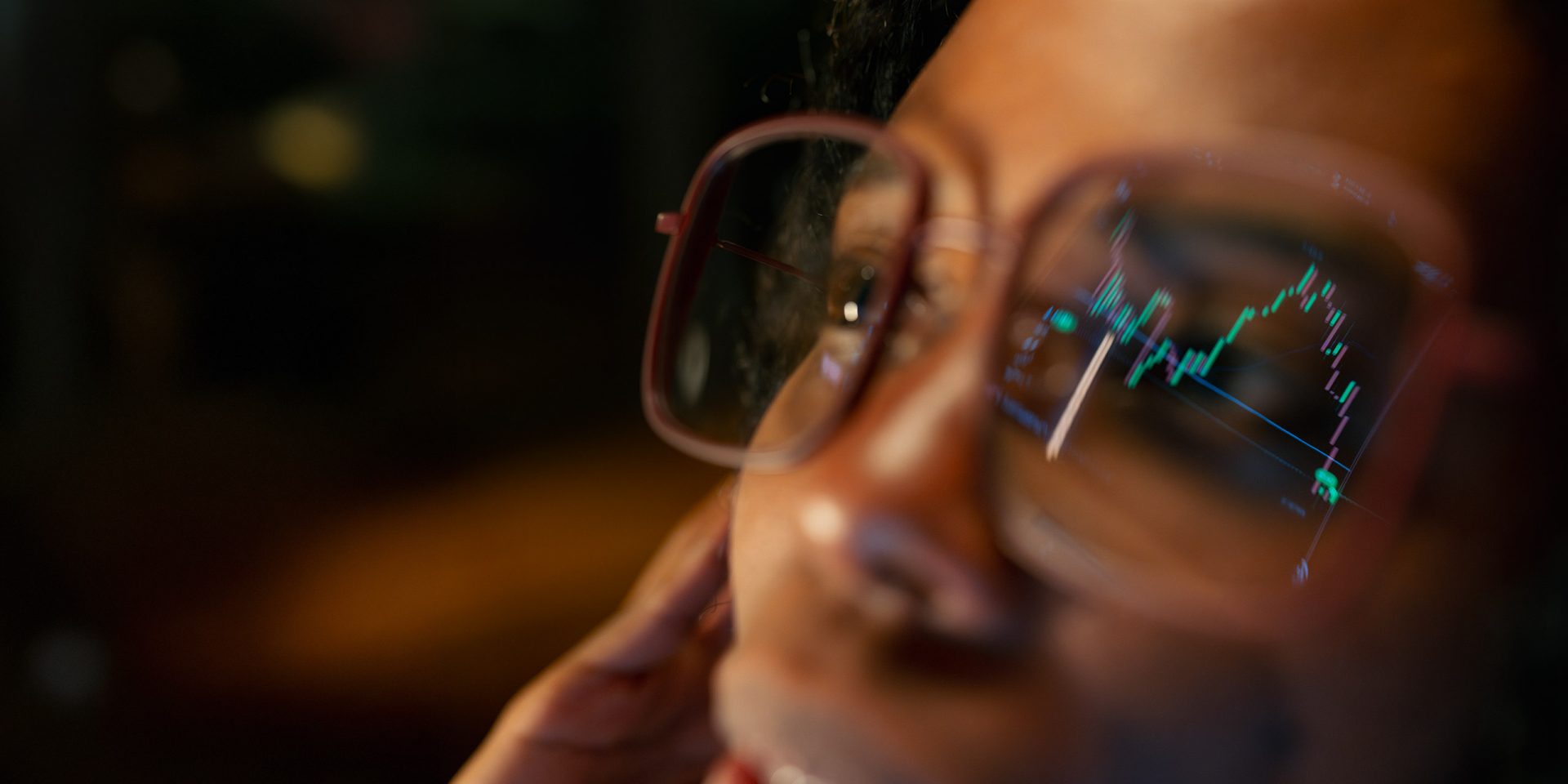 In der Brille einer Frau spiegeln sich Aktienkurse; sie beobachtet den Stand ihres Depots, das sie bei der norisbank eröffnet hat.