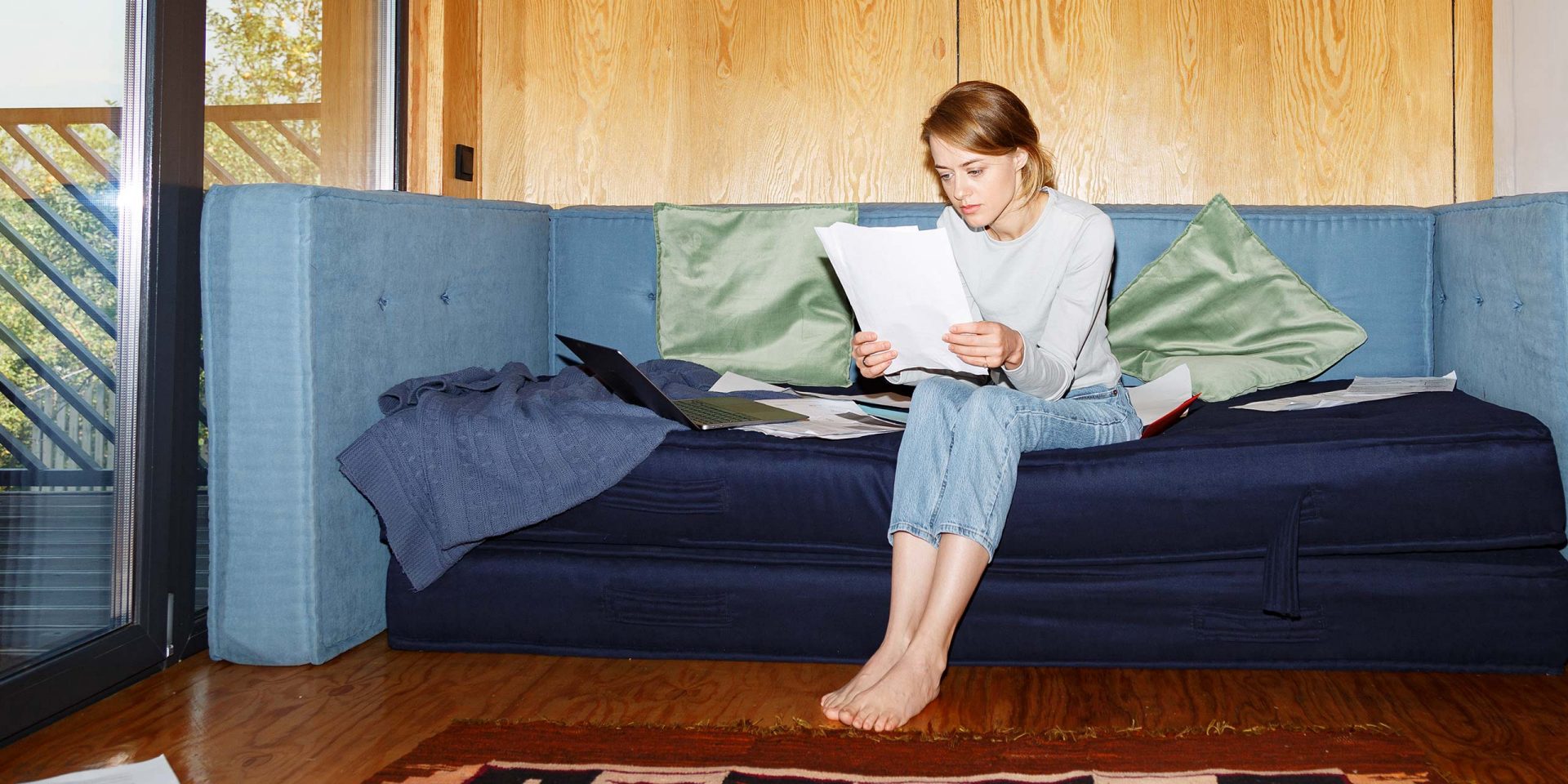 Junge Frau sitzt auf dem Sofa und prüft ihren Mietvertrag auf mögliche Fallen.