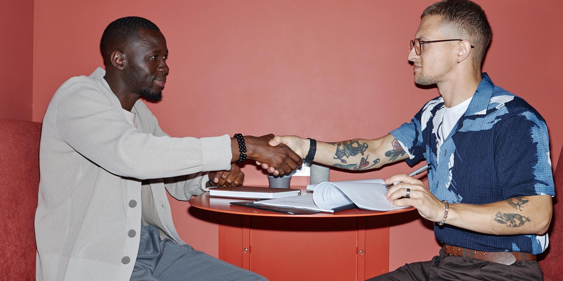 Symbolbild für "Kreditwissen". Zwei Männer geben sich am Tisch die Hand.