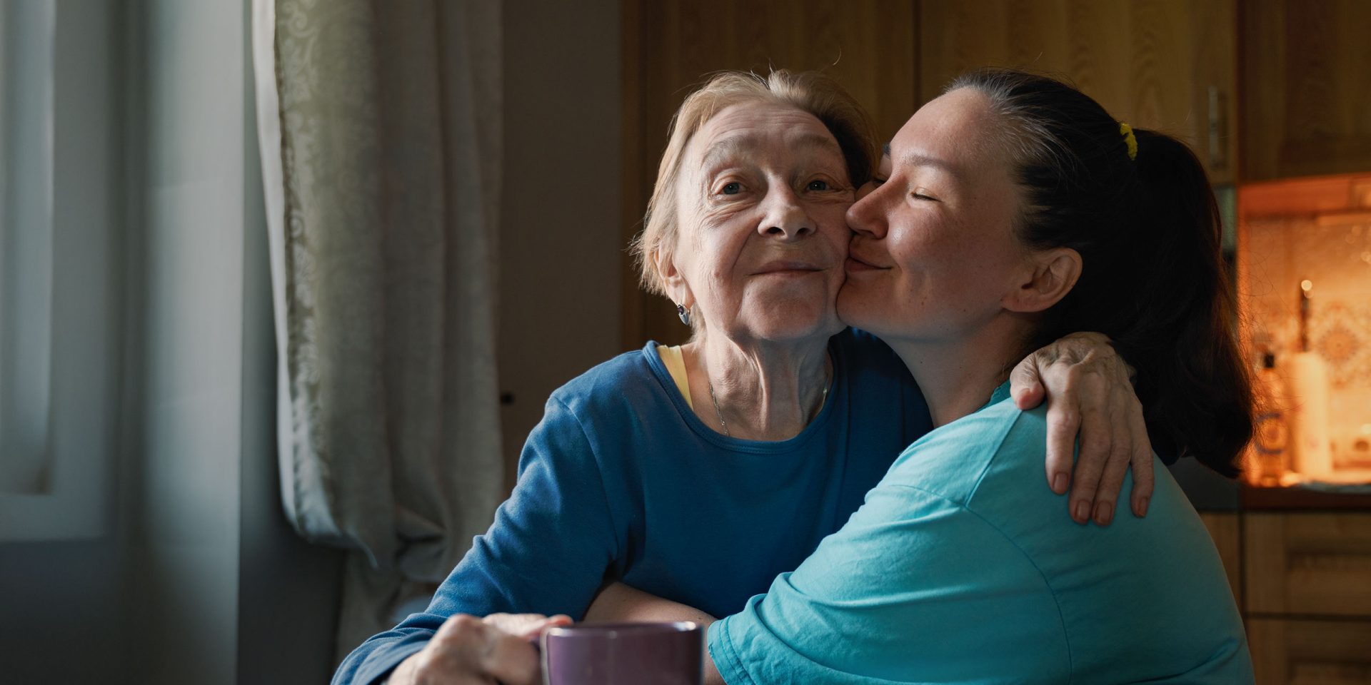 Eine junge Frau in gerichtlich bestellter Betreuung umarmt eine betagte ältere Frau.