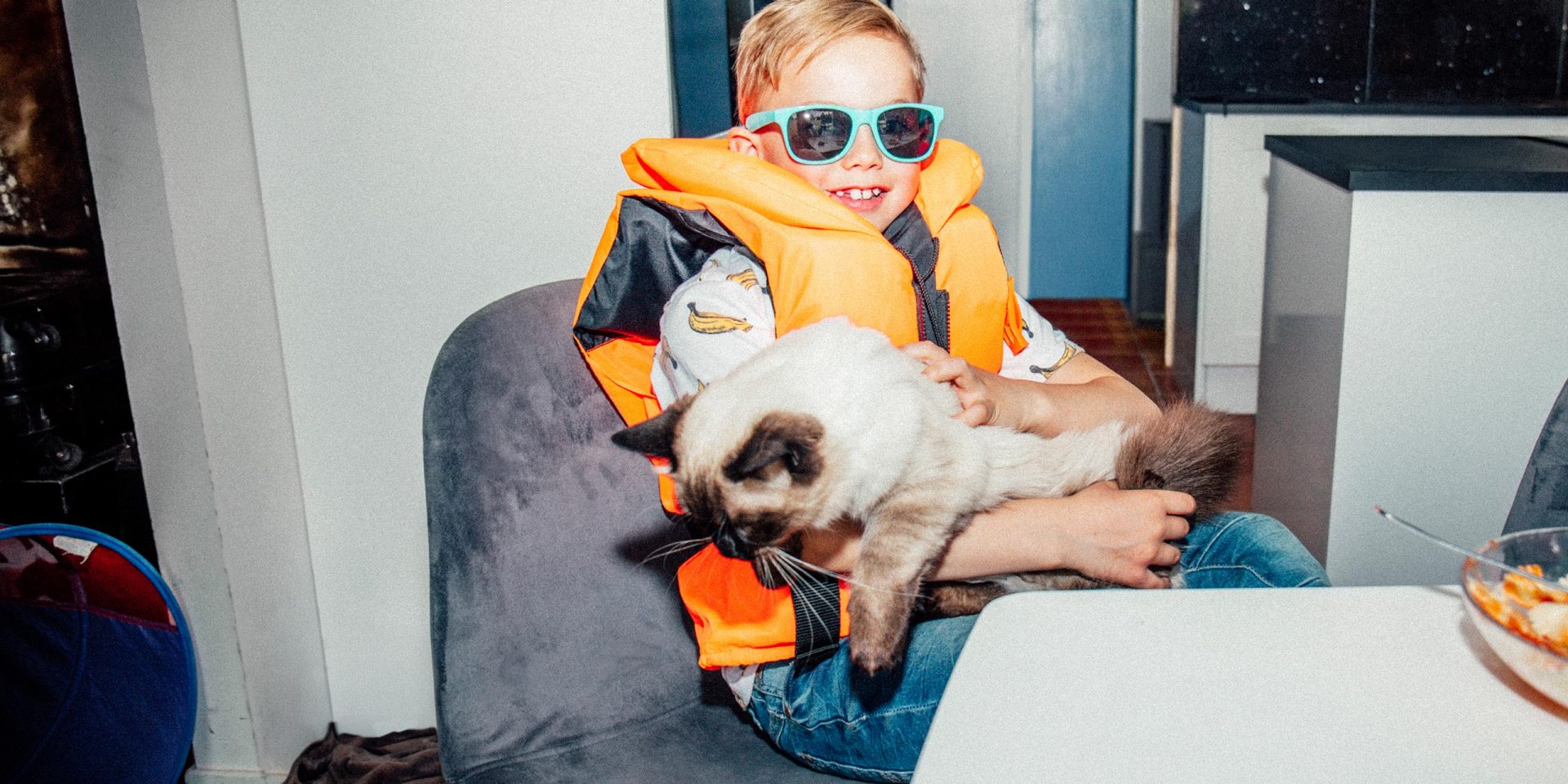 Porträt eines lächelnden Jungen mit Katze am Tisch. Symbolbild für "norisbank Kontakt".