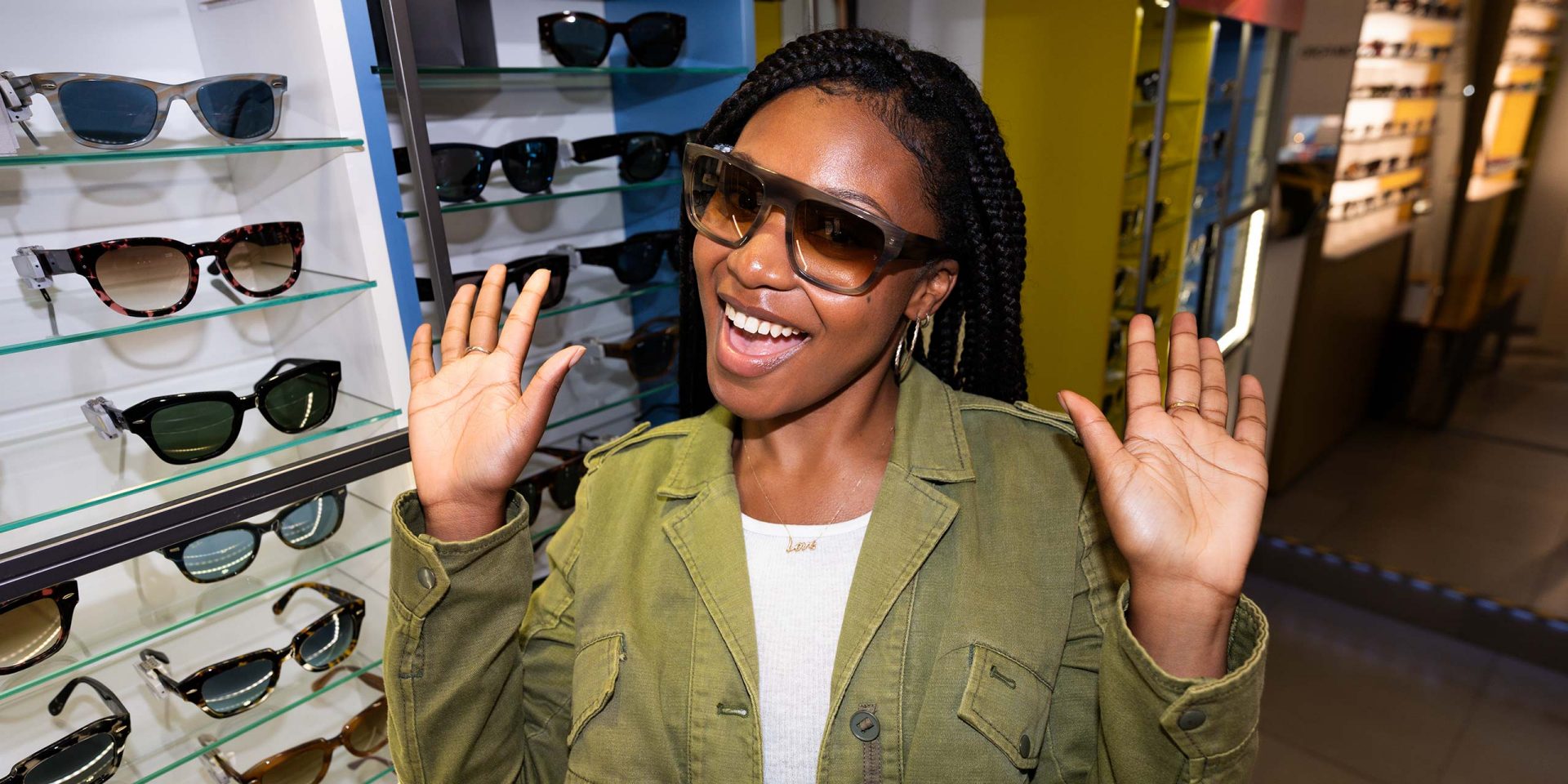 Eine Frau probiert eine Sonnenbrille bei einem Optiker aus und schaut in die Kamera. Symbolbild für "Konsumentenkredit".