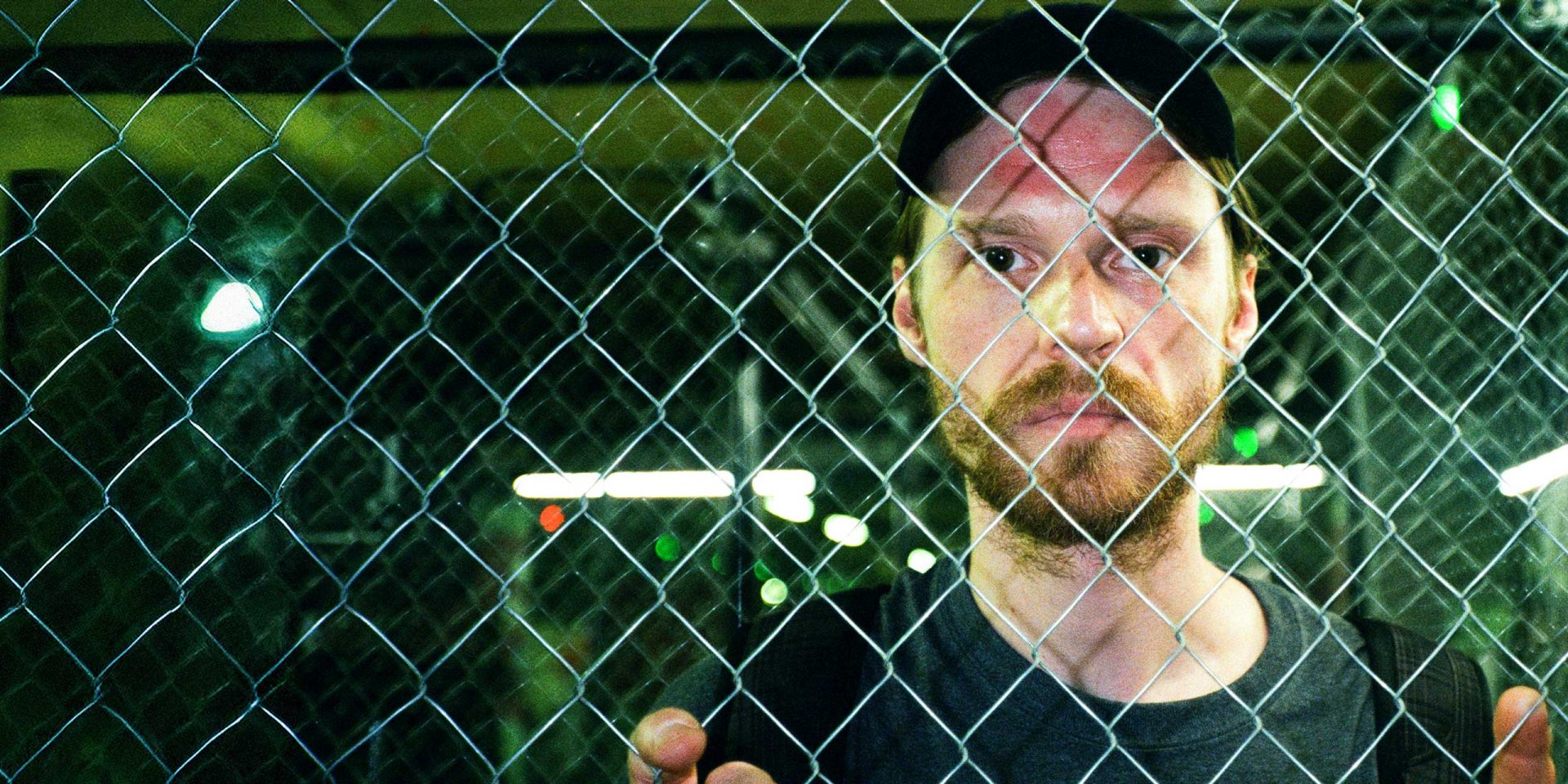 Verzweifelter Mann hinter einem Zaun. Symbolbild für "Konto gesperrt trotz Guthaben".