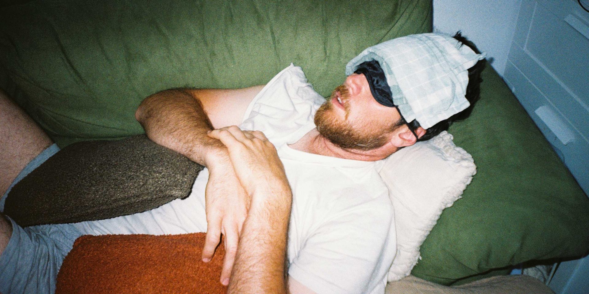 Mann mit Augenbinde liegt auf dem Sofa und kühlt seine Stirn. Symbolbild für "Konto überzogen".