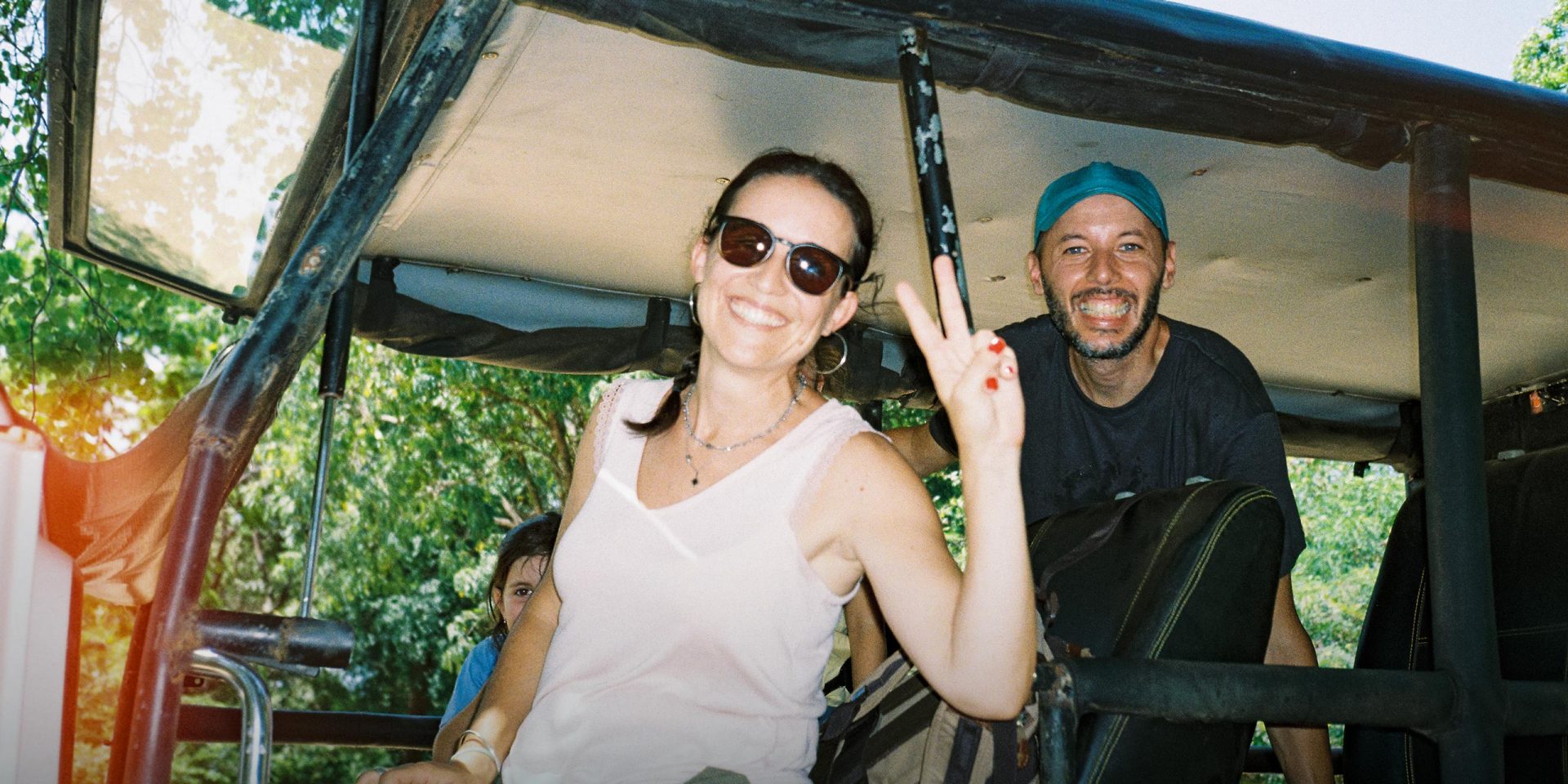 Eine Frau im Urlaub lässt sich fotografieren und macht das Peace-Zeichen. Symbolbild für "Kreditkarte im Ausland"