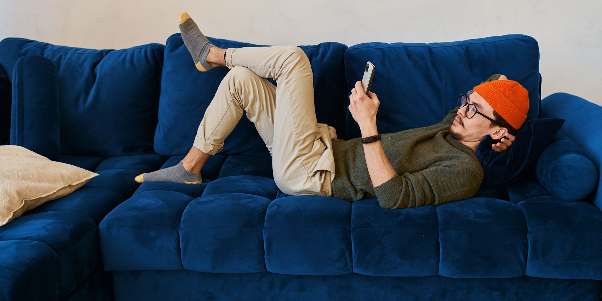 Mann liegt auf dem Sofa und recherchiert zu Kreditkartenbetrug