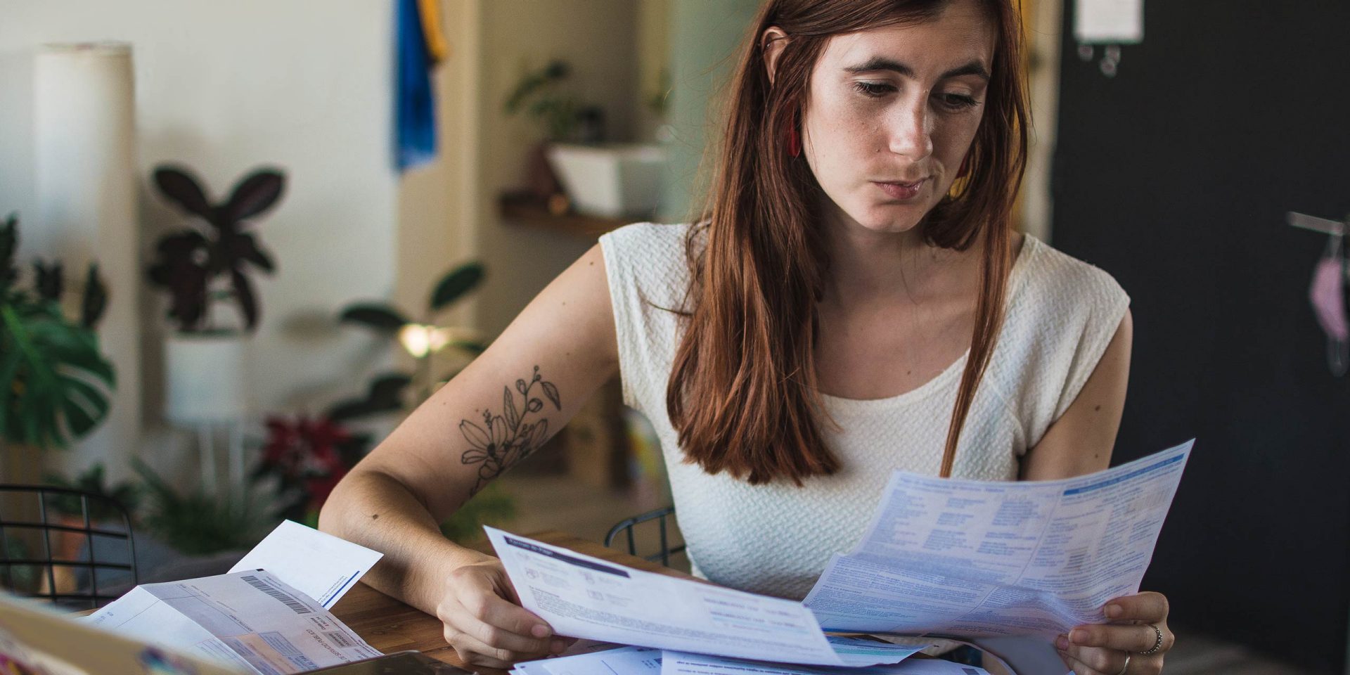 Eine Frau hat einen Todesfall bei der Bank gemeldet und ordnet am Schreibtisch Dokumente, und ist der Meldepflicht nachgekommen.