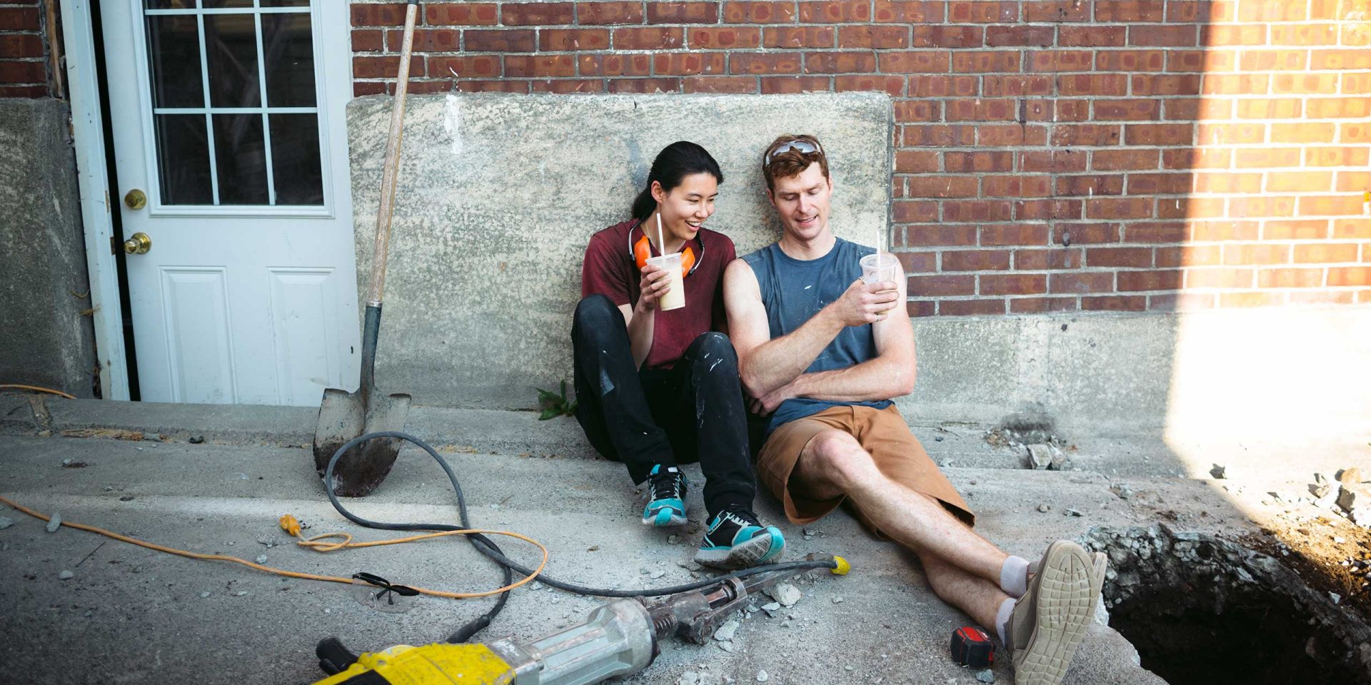 Ein paar sitzt vor seinem Haus und enstpannt sich von den Renovierungsarbeiten. Symboldbild für "Modernisierungskosten" bzw. "Renovierungskosten".