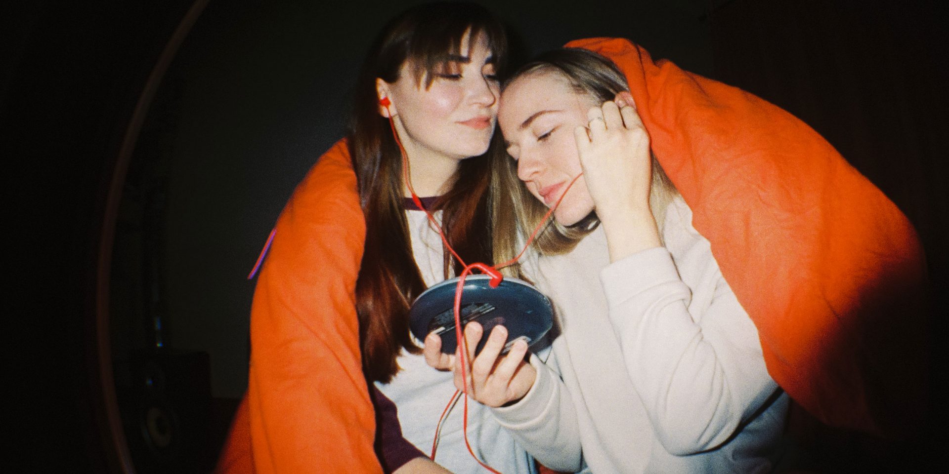 Zwei Freundinnen teilen sich die Kopfhörer eines Discmans. Symbolbild für "Multibanking"