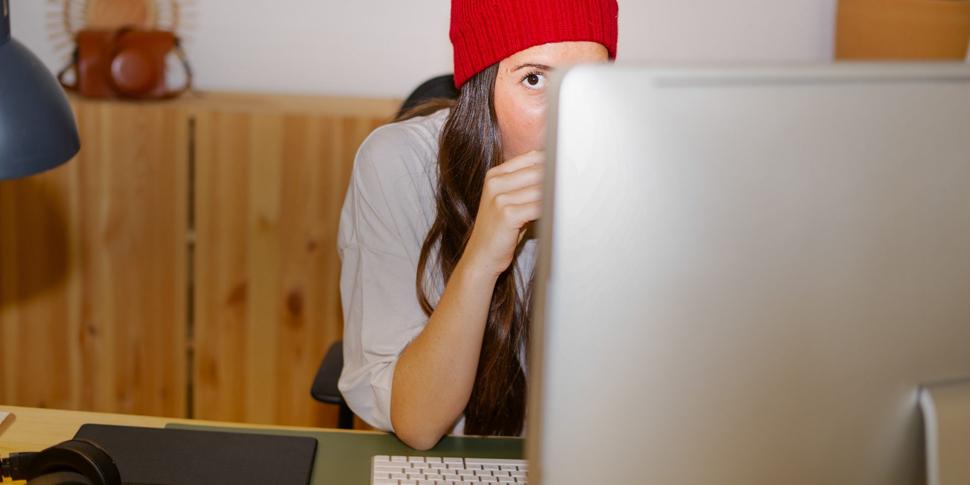 Eine Frau schaut hinter einem Computerbildschirm hervor – sie liest den Newsletter der norisbank.