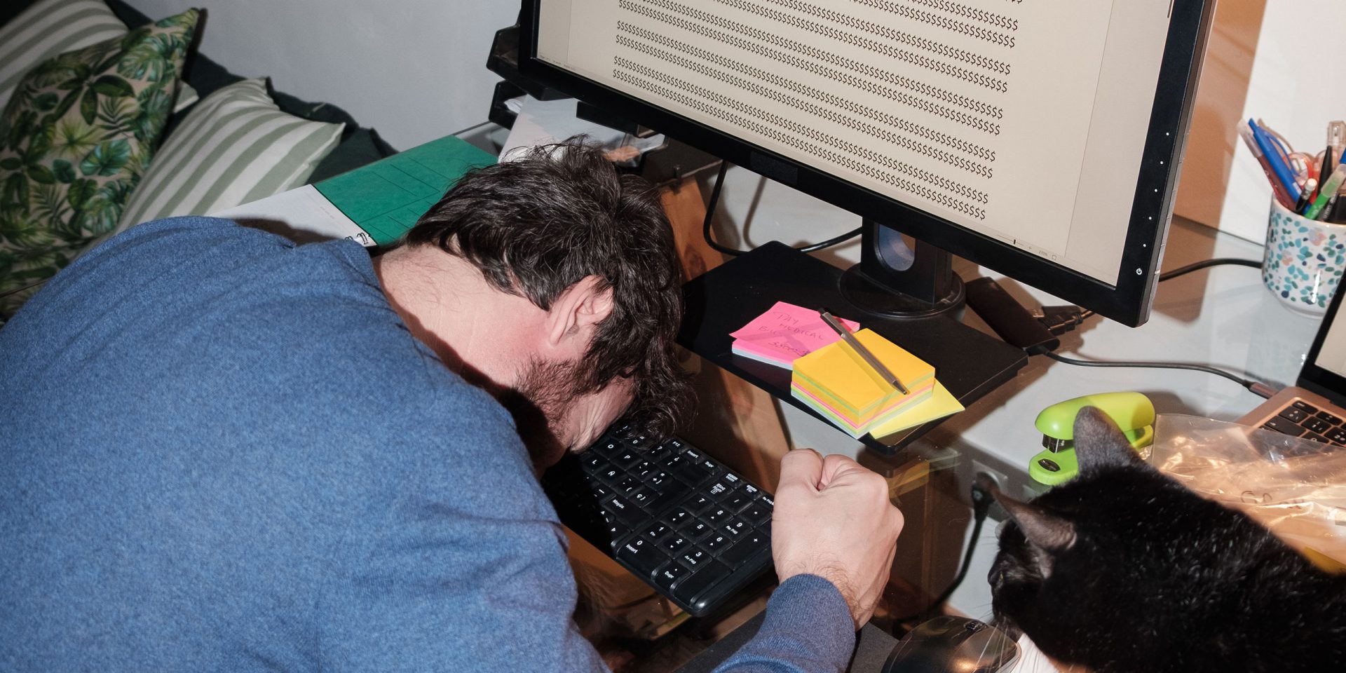 Erschöpfte Person legt den Kopf auf den Schreibtisch. Symbolbild für "Pfändungsschutzkonto".