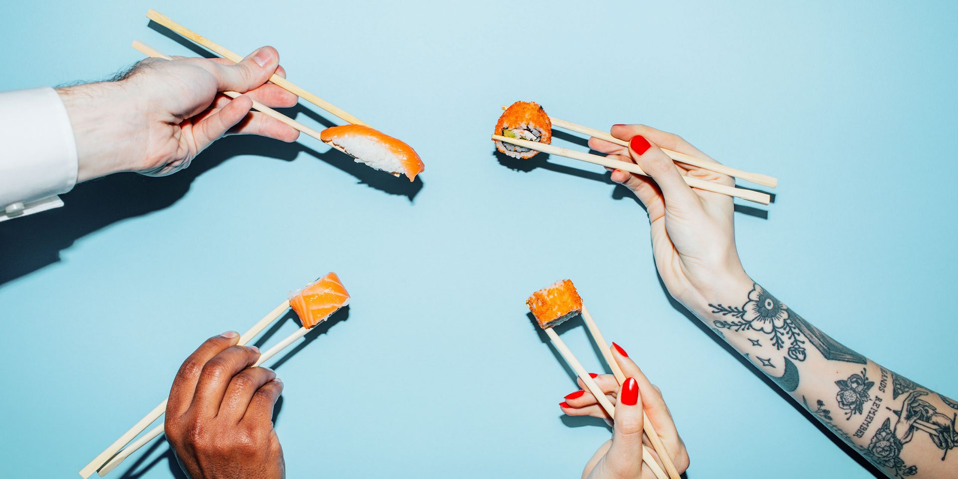 Nahaufnahme von Händen, die mit Stäbchen Sushi halten: Symbolbild für "Phising"