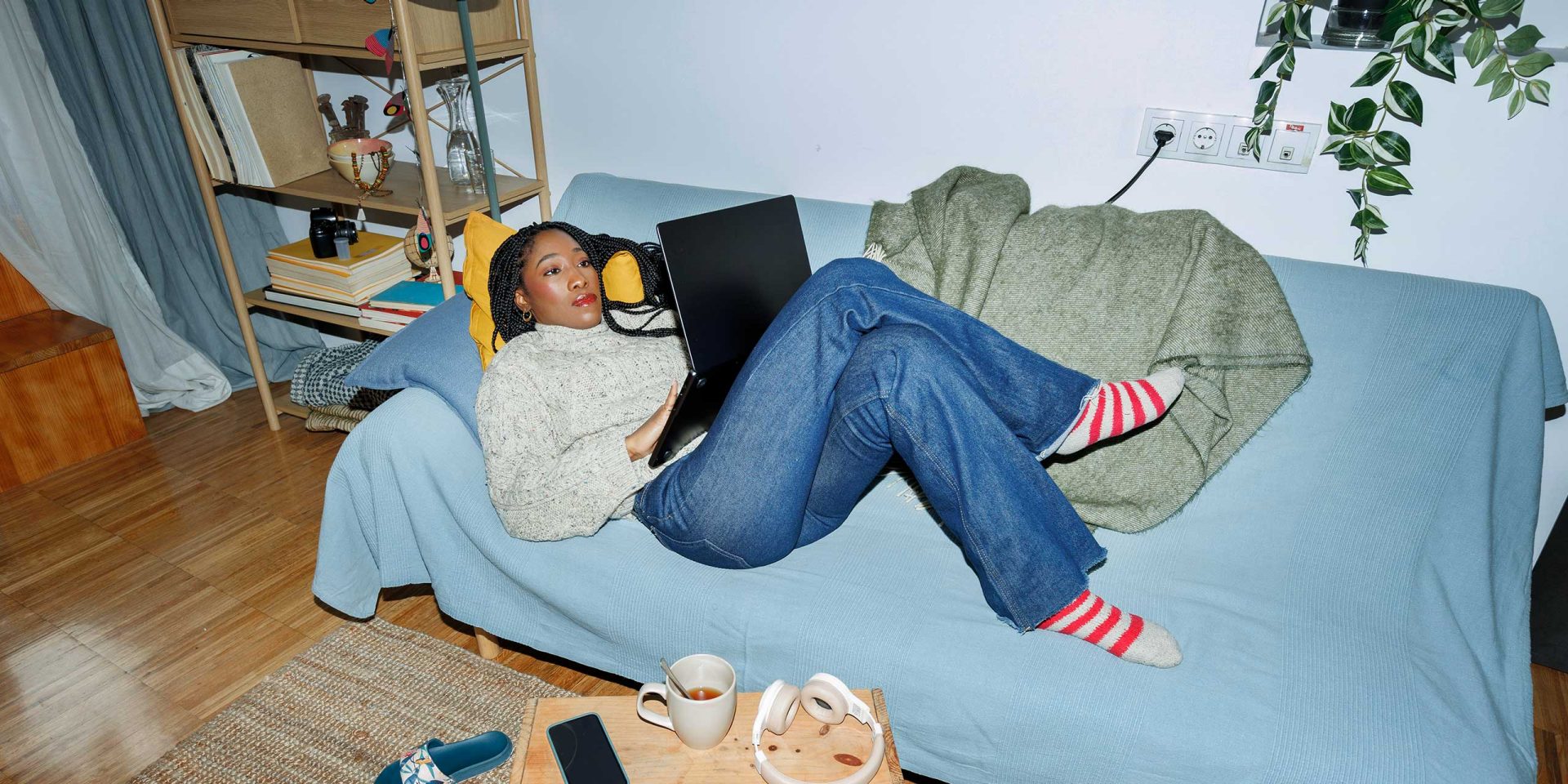 Person liegt auf dem Sofa mit Laptop – Symbolbild für "Saldo Bedeutung".