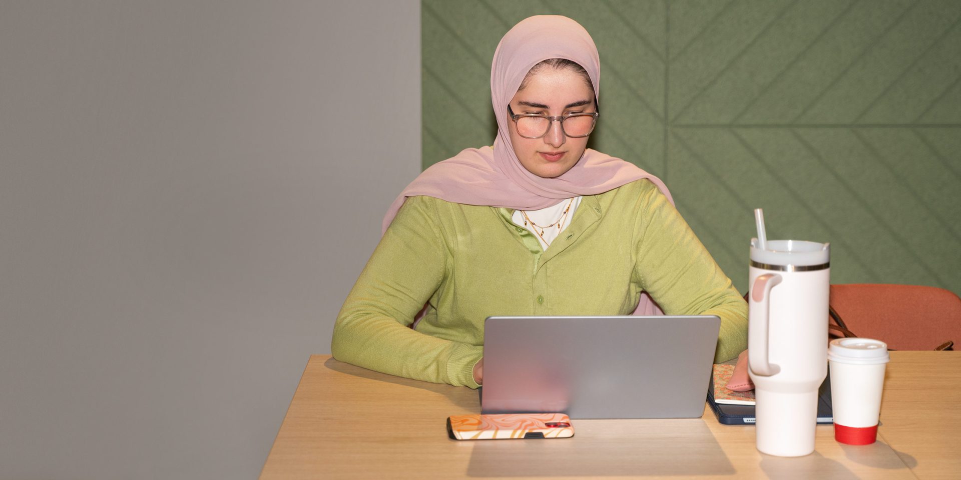 Eine junge Frau sitzt vor ihrem Laptop und sucht auf der norisbank Serviceseite nach den passenden Antworten zu ihren Finanzfragen.
