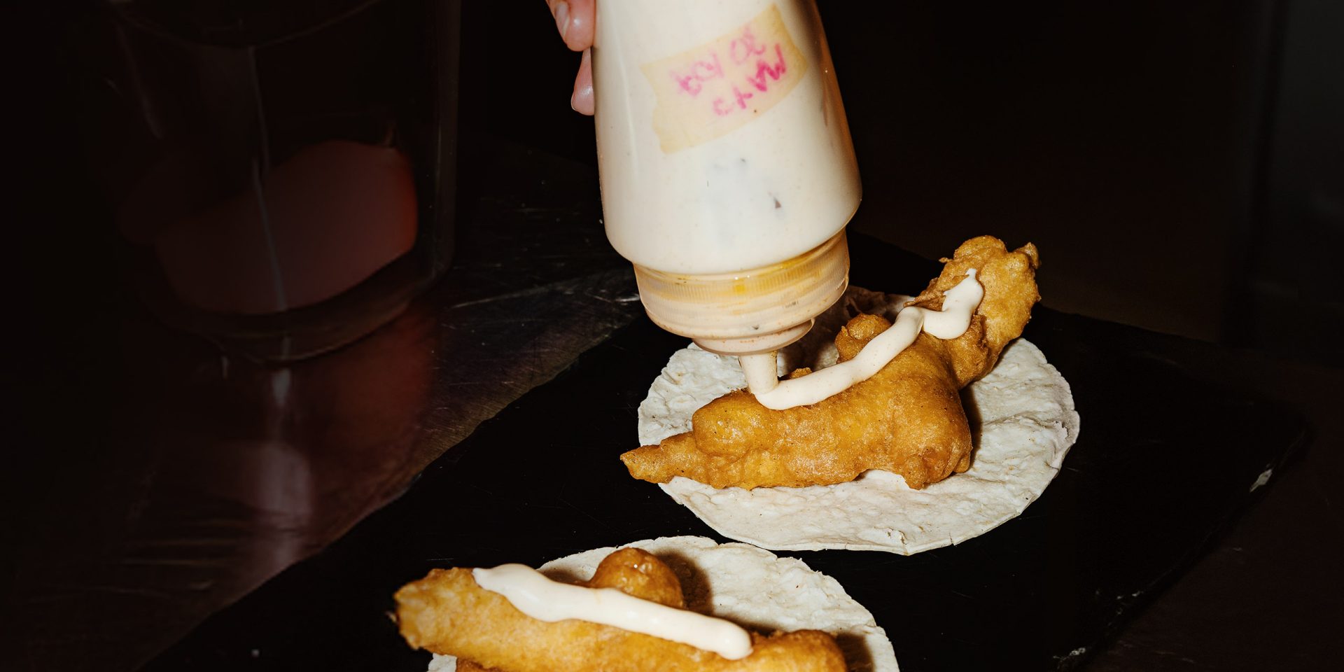 Symbolbild für "Sondertilgung": Nahaufnahme einer  Person, die sich extra Mayonnaise auf Fastfood drückt.