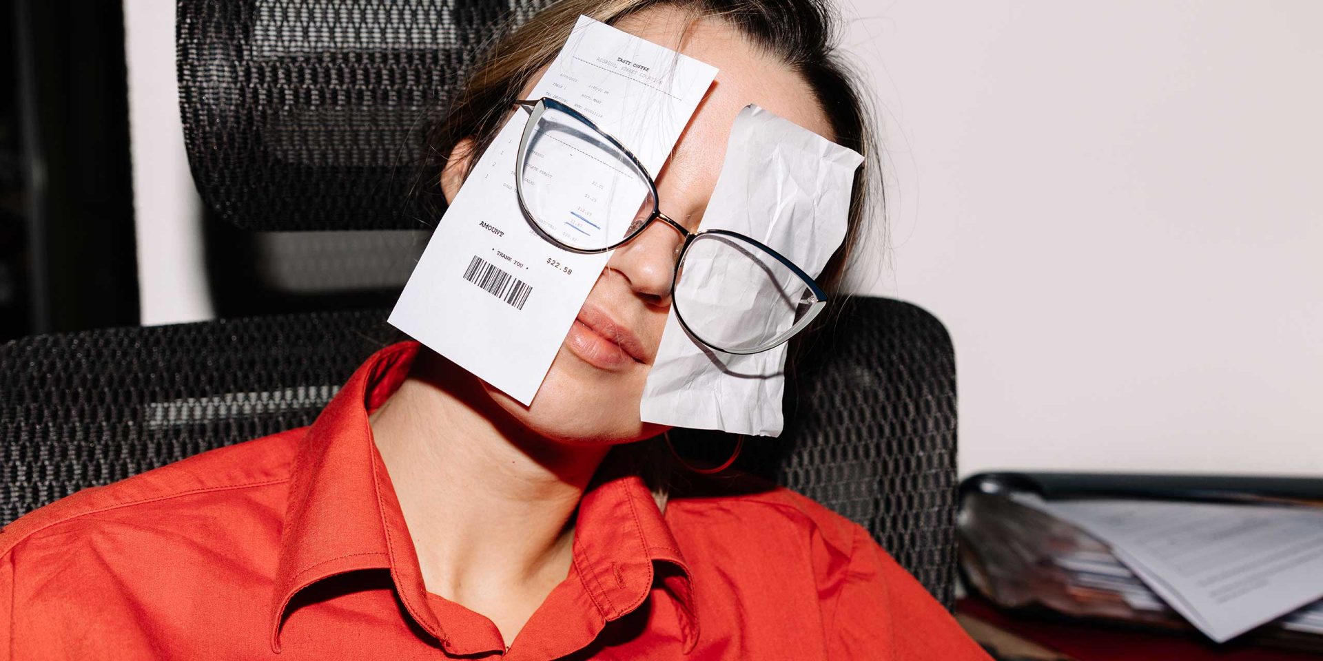 Studentin hat sich Einkaufsquittungen hinter die Brille geklemmt. Symbolbild für "Sparen als Student".