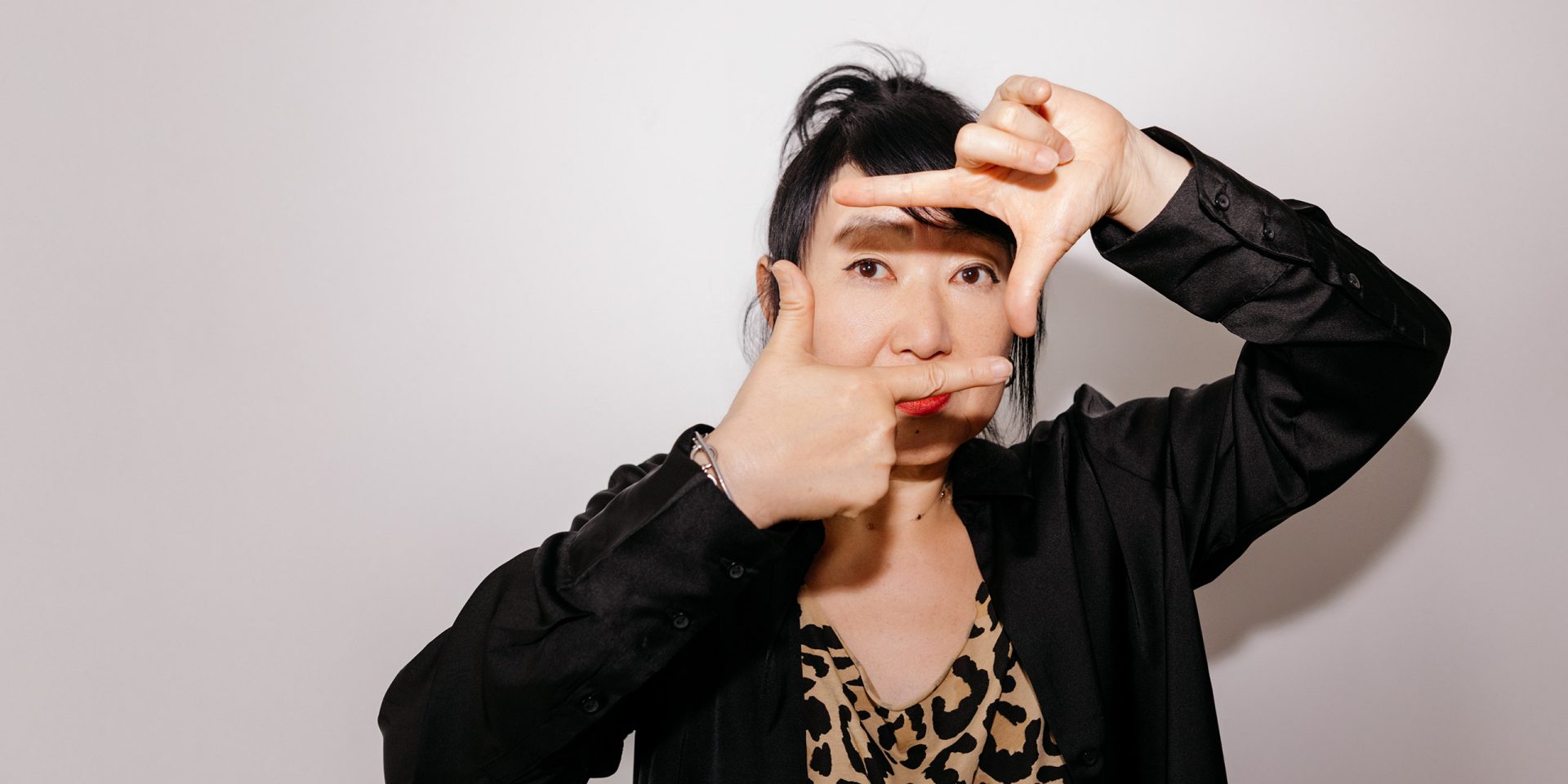 Eine Frau zeigt mit ihren Händen eine Raute vor ihrem Gesicht, Symbolbild für "Rahmenkredit"