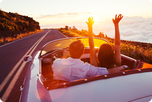 Junges Paar hat mit einem Privatkredit Flitterwochen gebucht und fährt in einem Cabrio an der Westküste der USA entlang