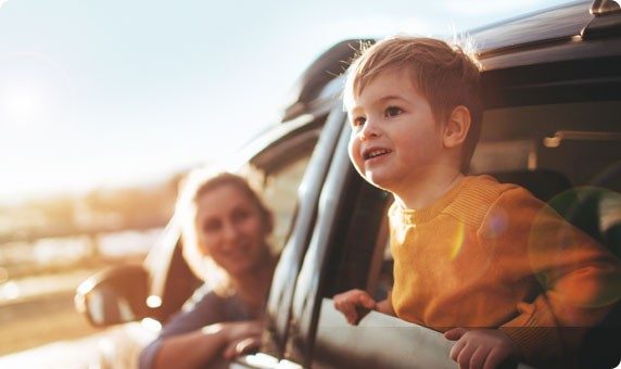 Eine Mutter und Ihr Kind schauen gespannt aus ihrem mit einem Autokredit finanzierten Auto