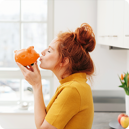 Eine Frau freut sich mit ihrem Sparschwein über hohe Tagesgeldzinsen.