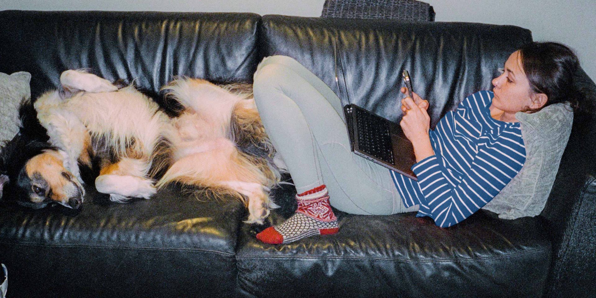 Junge Frau klärt ihre Fragen zum Konto entspannt vom Sofa aus.